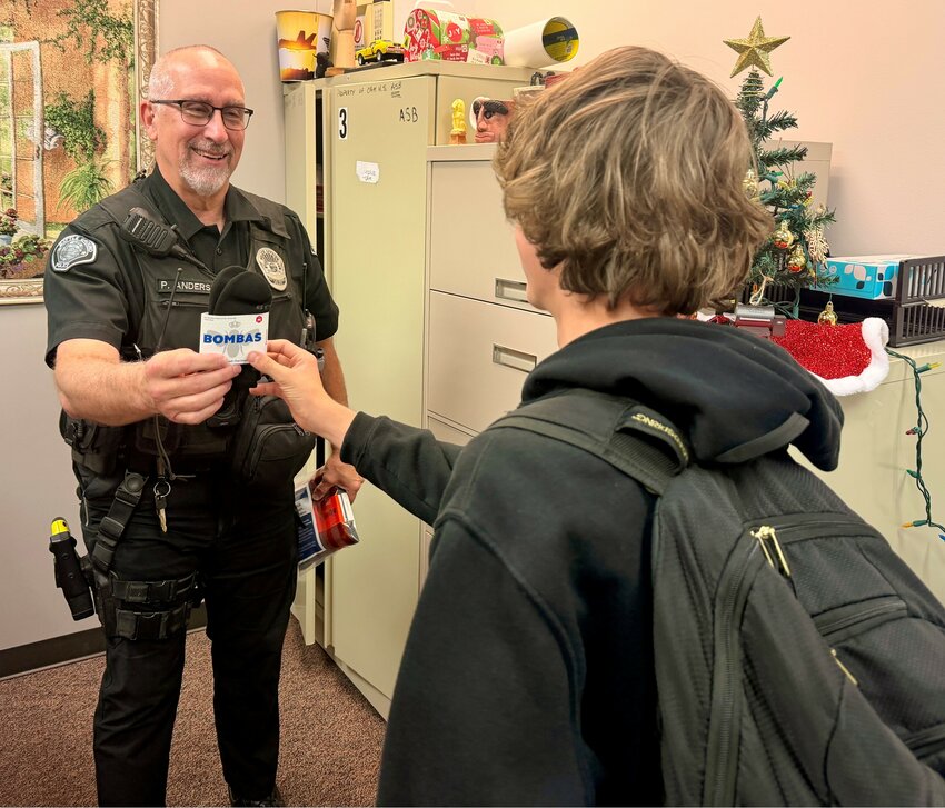 A Battle Ground Police Department Student Resource Officer, Phil Anderson, hands a pair of socks to a student as part of the new S.O.C.K. initiative.