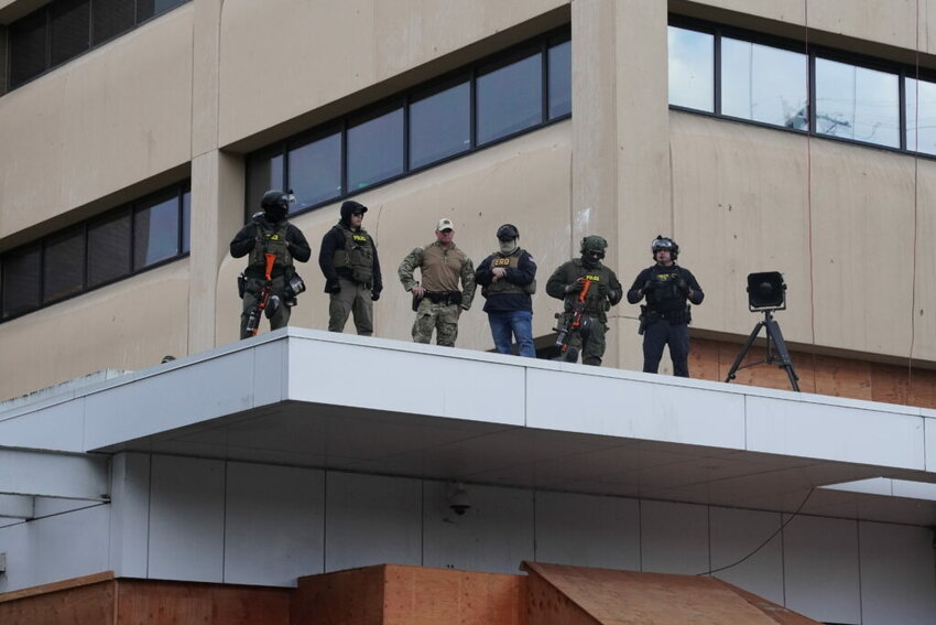 Federal officers with pepper-ball guns look down at protestors at the ICE facility south of downtown Portland on Sunday, Oct. 12, 2025. (Photo by Alex Baumhardt/Oregon Capital Chronicle)