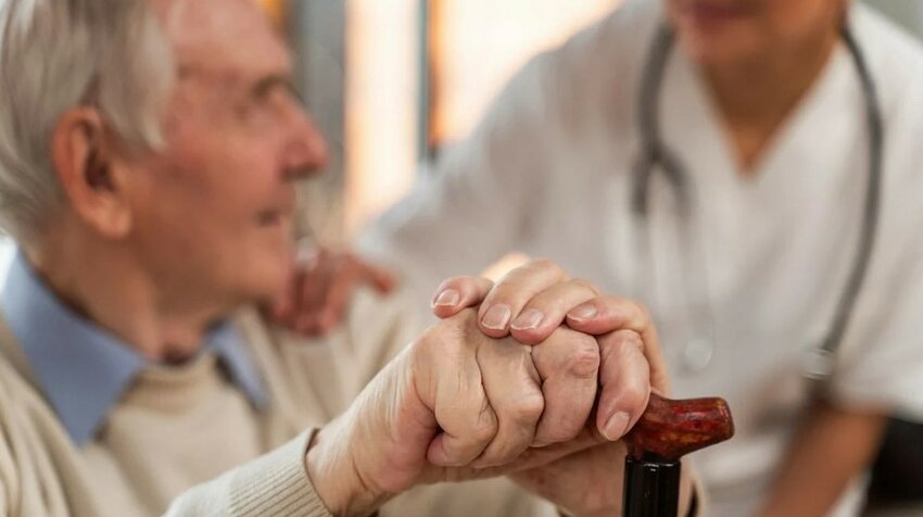 An elderly man with a cane receives support from a doctor.