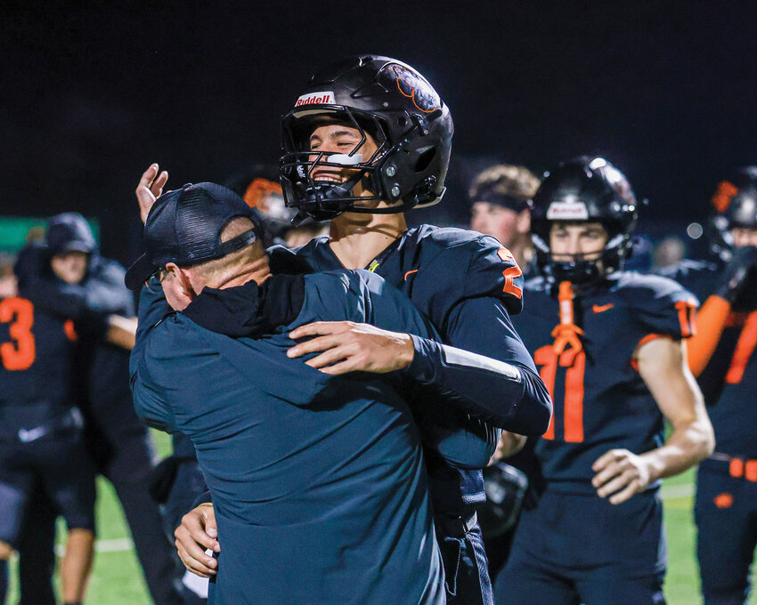Battle Ground senior quarterback Ethan Adams embraces head coach Mike Woodward after their postseason-clinching 38-14 win over Union High School on Thursday, Oct. 30.
