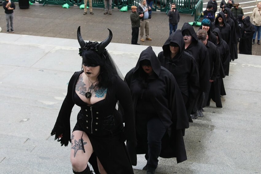 FILE PHOTO &mdash; Angel, who goes by one name and is the ritual guild leader for the Satanic Temple of Washington State, leads the procession up the capitol steps as part of their ritual in 2020.