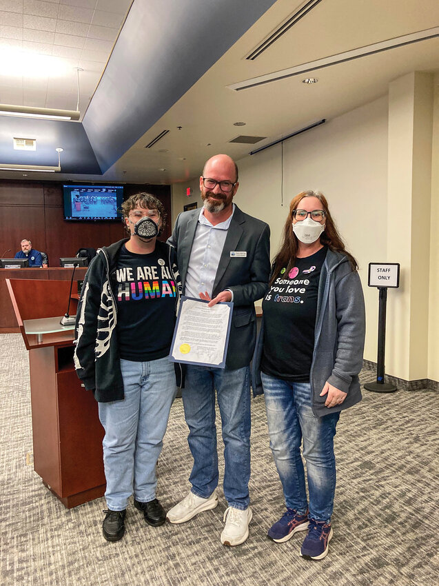 Battle Ground Mayor Troy McCoy holds a Transgender Day of Remembrance proclamation alongside Jessica Cole, president of Evoke Cascadia, and writer Simon Graves during the Nov. 17 council meeting in Battle Ground. The proclamation marked the city&rsquo;s first recognition of the observance and followed last year&rsquo;s conflict over the removal of a Pride Month proclamation.