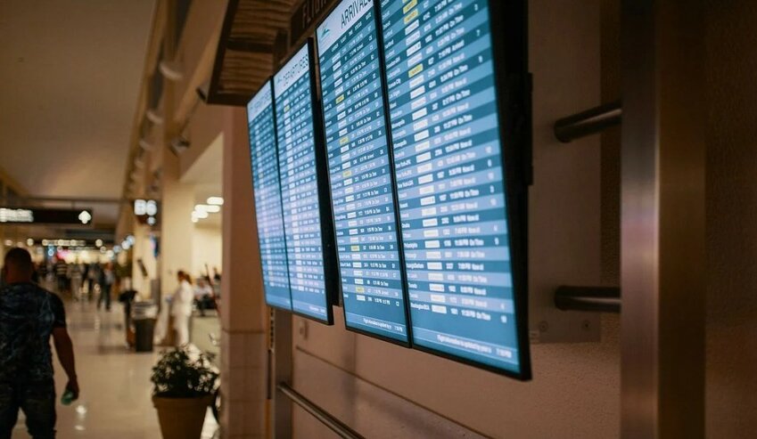 Digital screens display flight arrival and departure information inside an airport terminal.