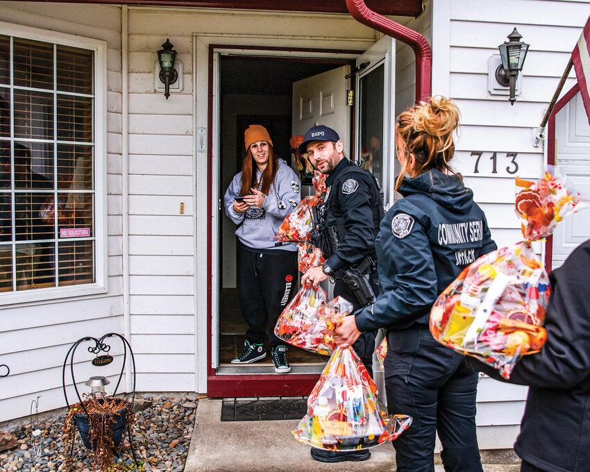 Battle Ground community member Brittany Knapp opens the door to Battle Ground police officer Liviu Balaceanu and other department staff delivering Thanksgiving meals for her family on Tuesday, Nov. 25.