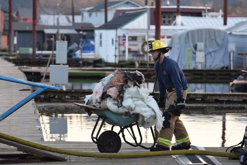 A Clark-Cowlitz Fire Rescue worker carries debris from CCFR&rsquo;s damaged Ridgefield boathouse after a fire was extinguished Monday afternoon.