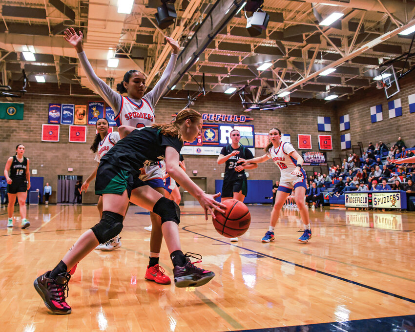 Woodland sophomore Makynzie Guthrie scoots by Ridgefield senior Savannah Chanda along the baseline during Woodland&rsquo;s 43-31 win over Ridgefield on Tuesday, Dec. 9.