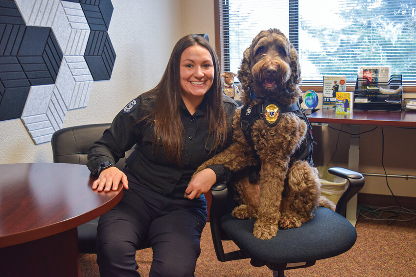 Paramedic Supervisor Kanessa Thompson sits beside Apollo at the American Medical Response office in Hazel Dell. Thompson is an AMR operations supervisor and paramedic who works alongside Apollo as his handler during daily operations and support visits.