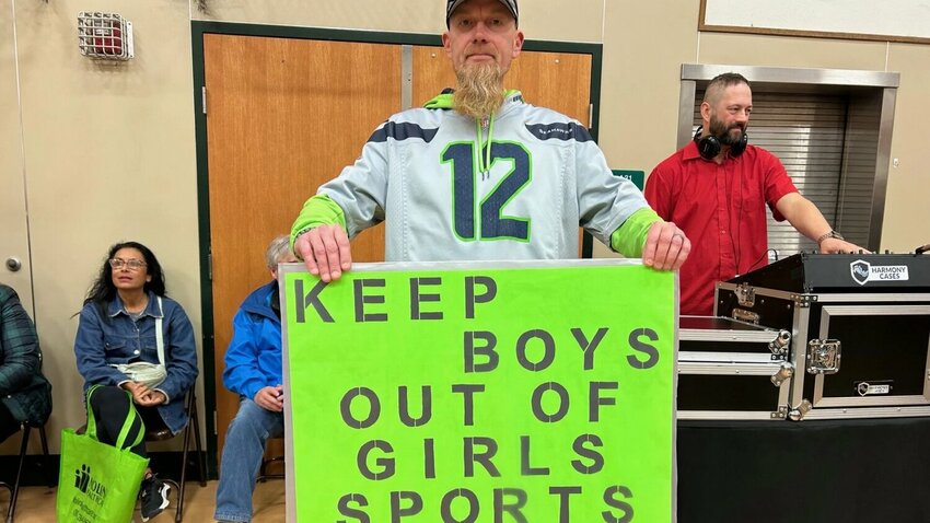 A Tumwater rallygoer carrying sign in support of a statewide initiative to protect girls in sports by keeping biological males out.