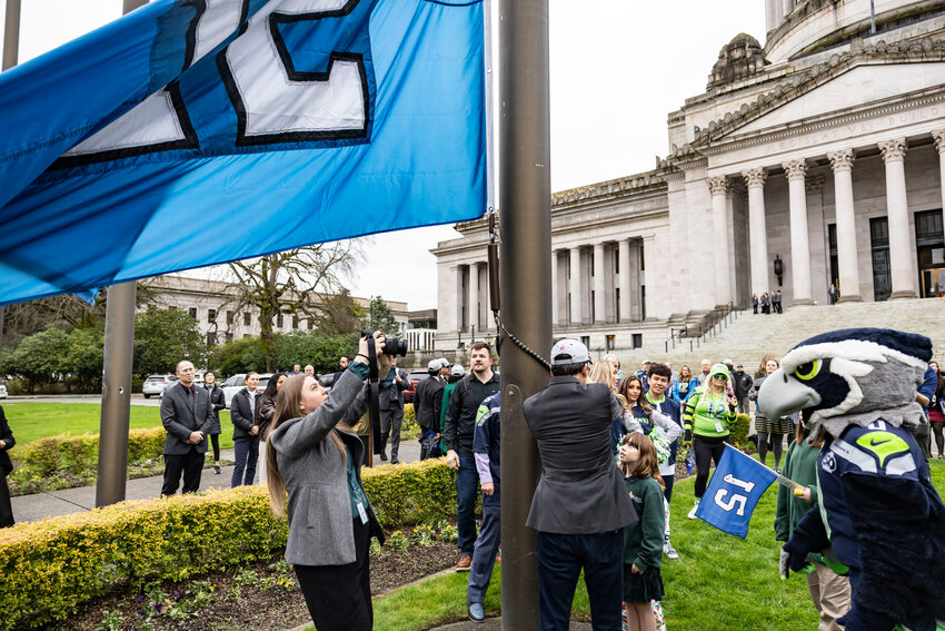 Gov. Bob Ferguson raises the &ldquo;12&rdquo; flag with help from kids at the state Capitol in Olympia on Wednesday, Jan. 14.