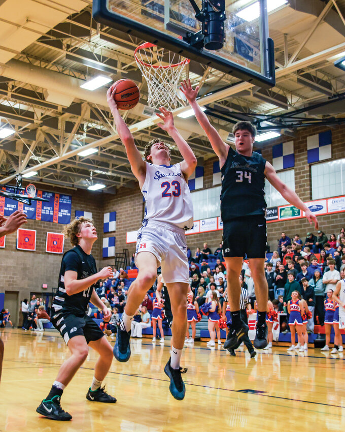 Ridgefield senior Gavin Perry, No. 23, goes up for a basket as Woodland defender Michael Belvin flies on by under the rim during Ridgefield&rsquo;s 62-46 win on Thursday, Jan. 15.