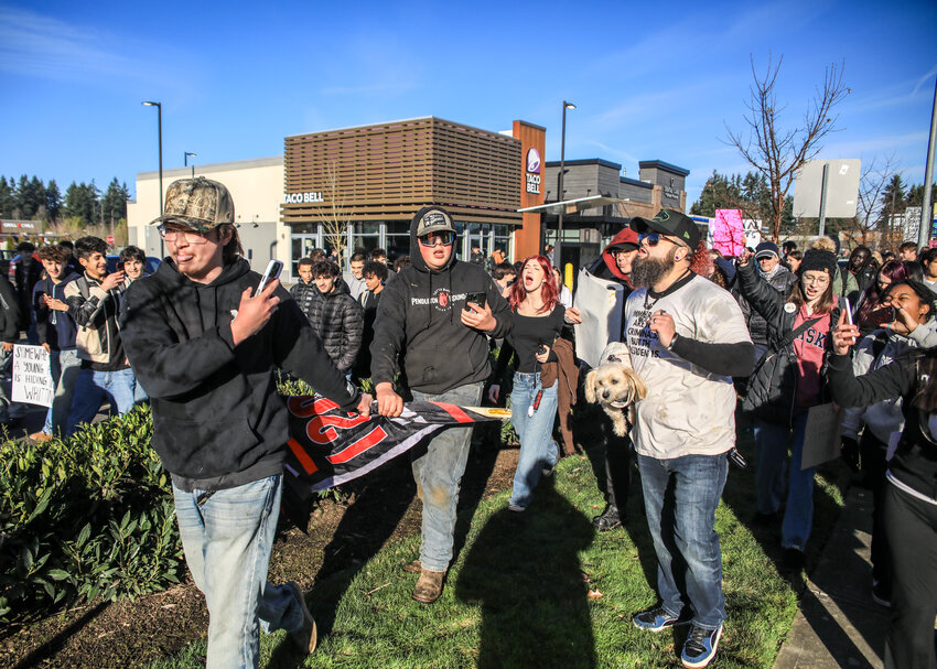 Counter-protesters carrying a flag that reads, &ldquo;Deport them all, I support ICE,&rdquo; to the Prairie High School student walkout opposing immigration enforcement are chased out by adults and students during the protest along state Route 503 on Tuesday, Jan. 20.