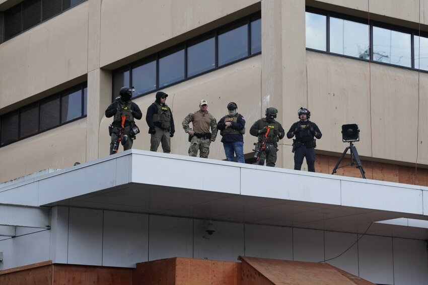 Federal officers with pepper-ball guns look down at protesters at the ICE facility south of downtown Portland on Sunday, Oct. 12, 2025. (Photo by Alex Baumhardt/Oregon Capital Chronicle)