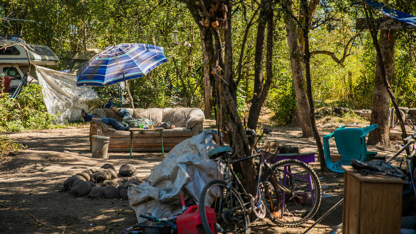 A man sleeps on a couch under an umbrella at the end of Eckerson Road in Centralia in 2022.