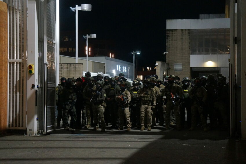 Federal police wait inside the gate of the Immigration and Customs Enforcement processing center south of downtown Portland during protests on Sunday, Oct. 6, 2025. (Photo by Alex Baumhardt/Oregon Capital Chronicle)