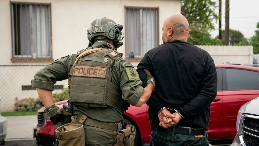 An ICE officer detains a handcuffed man in Los Angeles on June 12, 2025.