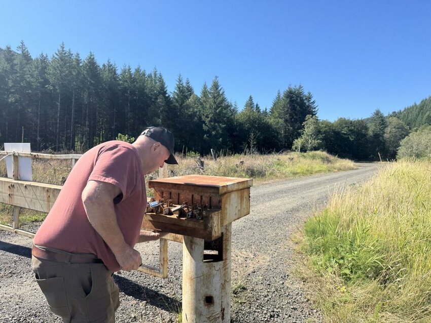 Wahkiakum County Commissioner Dan Cothren unlocks an American Forest Management gate after patrolling lands owned by prince-affiliated companies on Aug. 21, 2025. The gate blocks off driving access to thousands of acres of prime longtime hunting grounds. The patrol is a routine part of his part-time job as a security contractor for timberland owners.