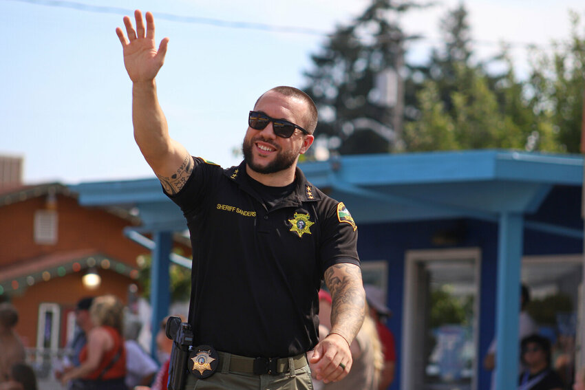 Thurston County Sheriff Derek Sanders waves to the crowd during the Rainier Round-Up Days Parade on Saturday, Aug. 23.