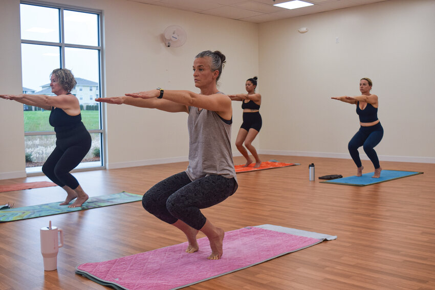 Participants at The Yoga Ridge perform the Awkward Pose (Utkatasana), focusing on lower-body strength and flexibility. The pose is part of the 26-posture sequence practiced in hot yoga sessions at the studio.