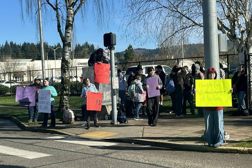 Protesters hold signs across the street from Mark Morris High School Tuesday, Feb. 10. They criticized what they described as a lack of response from the school after several students were accused of sexual assault.