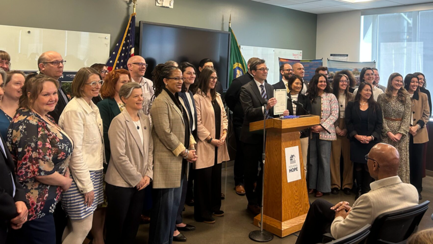 Washington Gov. Bob Ferguson stands alongside lawmakers and housing advocates after signing House Bill 2266 into law on Friday, March 27, 2026, in Everett. (Photo by Jake Goldstein-Street/Washington State Standard)