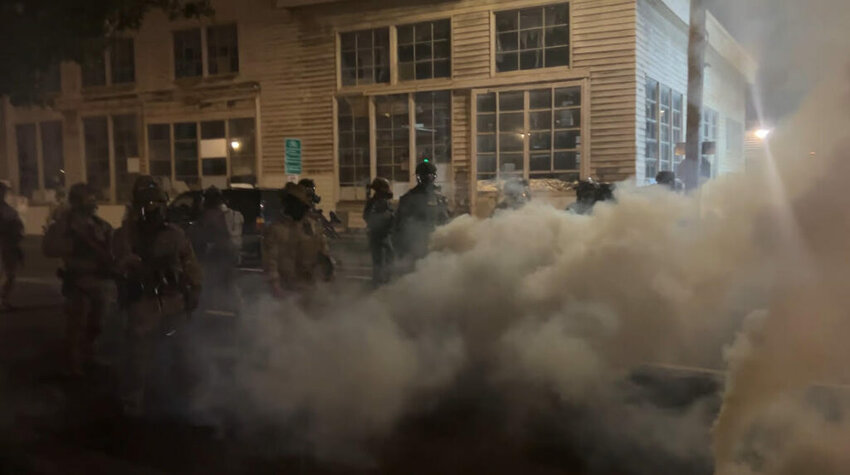 Federal officers throw flash bangs and tear gas at protesters as they move into a city block outside the Portland Immigration and Customs Enforcement facility on Oct. 5, 2025. (Photo by Alex Baumhardt/Oregon Capital Chronicle)