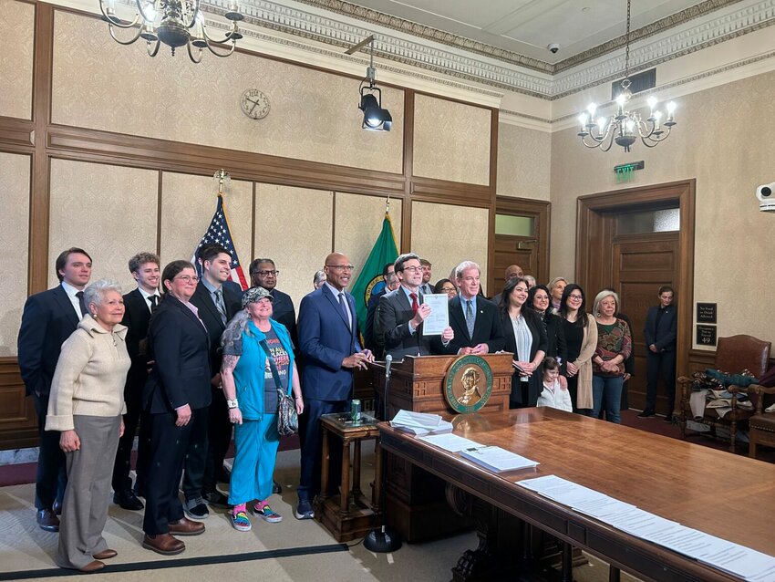Gov. Bob Ferguson holds up Senate Bill 5974, which sets heightened standards for sheriffs, alongside lawmakers and advocates after signing it on Wednesday, April 1, 2026, in Olympia, Washington. (Photo by Jake Goldstein-Street/Washington State Standard)