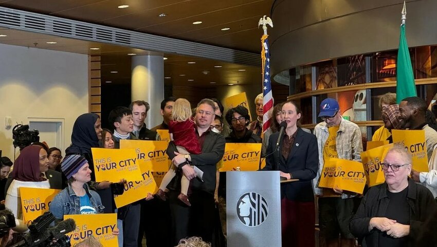 Seattle Mayor Katie Wilson speaks during her first address as mayor, surrounded by supporters holding signs.