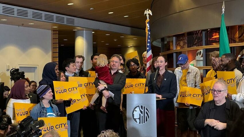 Seattle Mayor Katie Wilson speaks during her first address as mayor, surrounded by supporters holding signs.