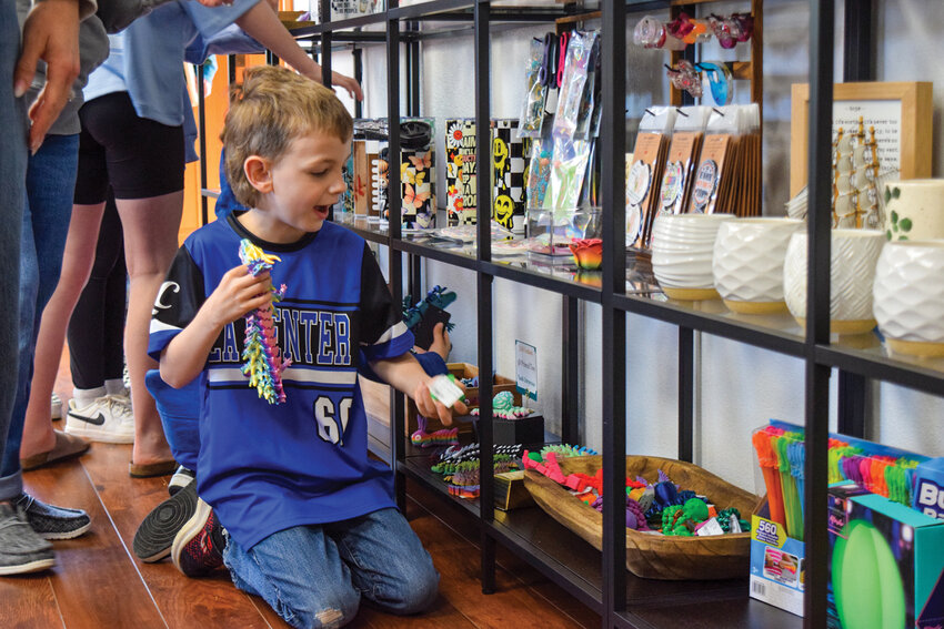 A young visitor examines a selection of small toys inside Create Joy on opening morning, Saturday, April 18. The shop offers a range of locally made gifts and goods now in La Center.