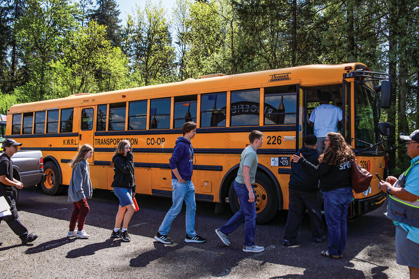 Students participating in an emergency simulation exercise get on a school bus at Ridgefield High School to be taken to an off-site location to be reunited with family members on Friday, April 24.