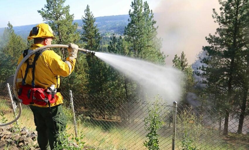 A firefighter sprays water while battling a wildfire near Spokane, Washington.