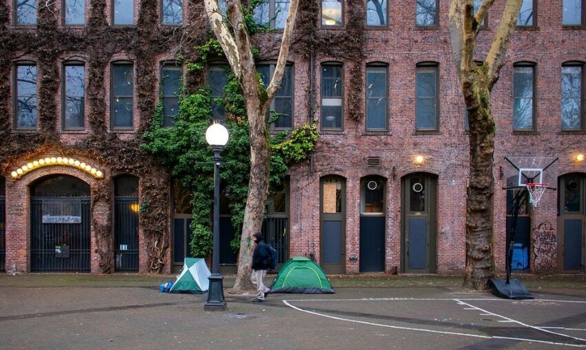 A homeless encampment with tents and tarps on a sidewalk in Seattle&rsquo;s Pioneer Square.