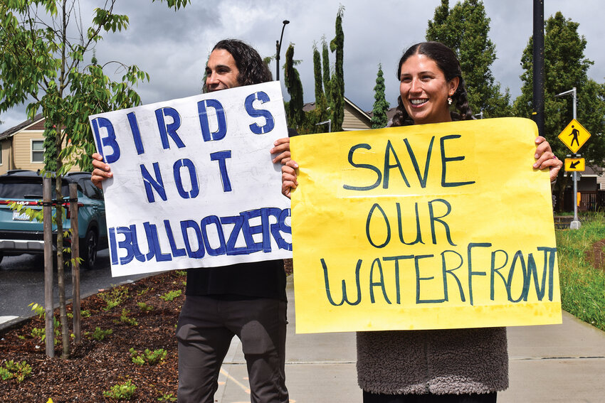 Two demonstrators wave signs reading &ldquo;Birds Not Bulldozers&rdquo; and &ldquo;Save Our Waterfront&rdquo; north of the intersection of Pioneer Street and Royle Road on Saturday, May 17. Community members gathered during a rainy afternoon to protest the Port of Ridgefield&rsquo;s proposed waterfront redevelopment plans.