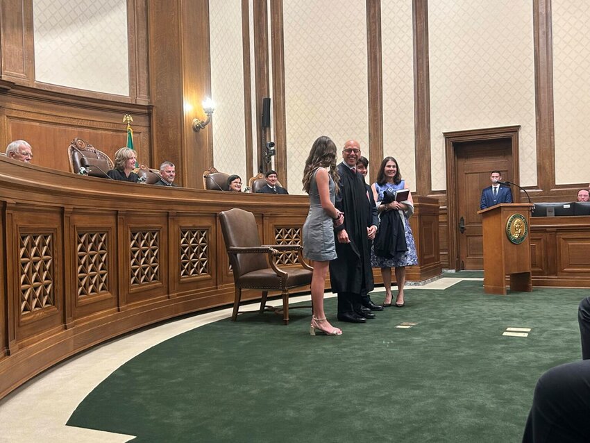Washington state Supreme Court Justice Theo Angelis dons his robe alongside wife Kim and children Katherine and John as he is sworn in as a justice at the Temple of Justice on Monday, May 18, 2026, in Olympia. (Photo by Jake Goldstein-Street/Washington State Standard)