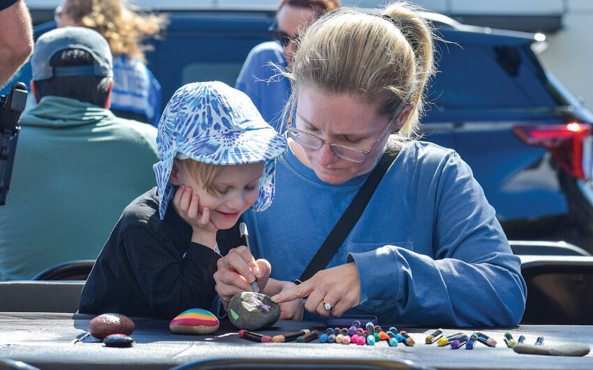 Families gather around painting tables at Overlook Park during the return of Rocks with Cops on Saturday, May 30. The free community event connected police officials with local participants and drew a strong turnout in its first year back after a multi-year hiatus.