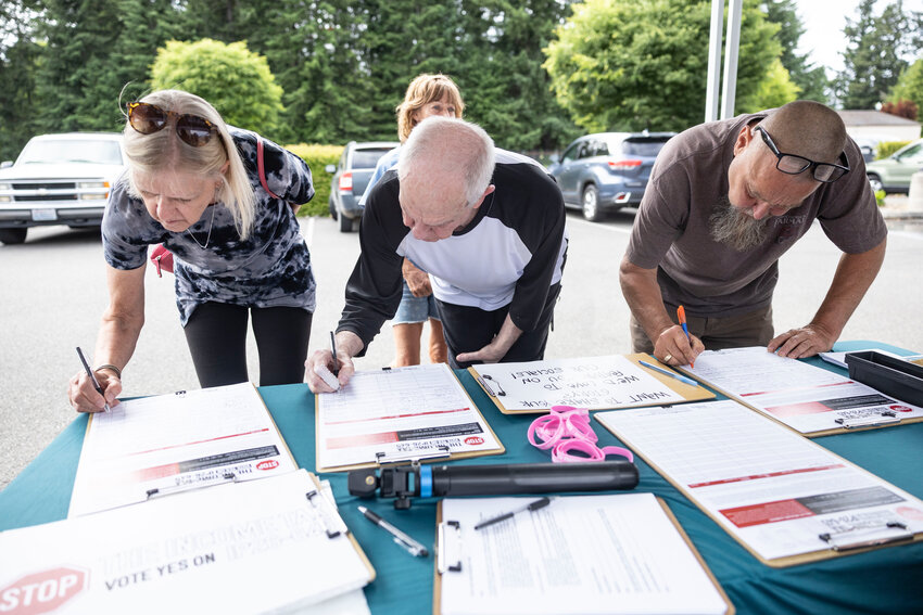 Attendees sign a petition to repeal the income tax at an event in Tumwater on Wednesday, June 3.