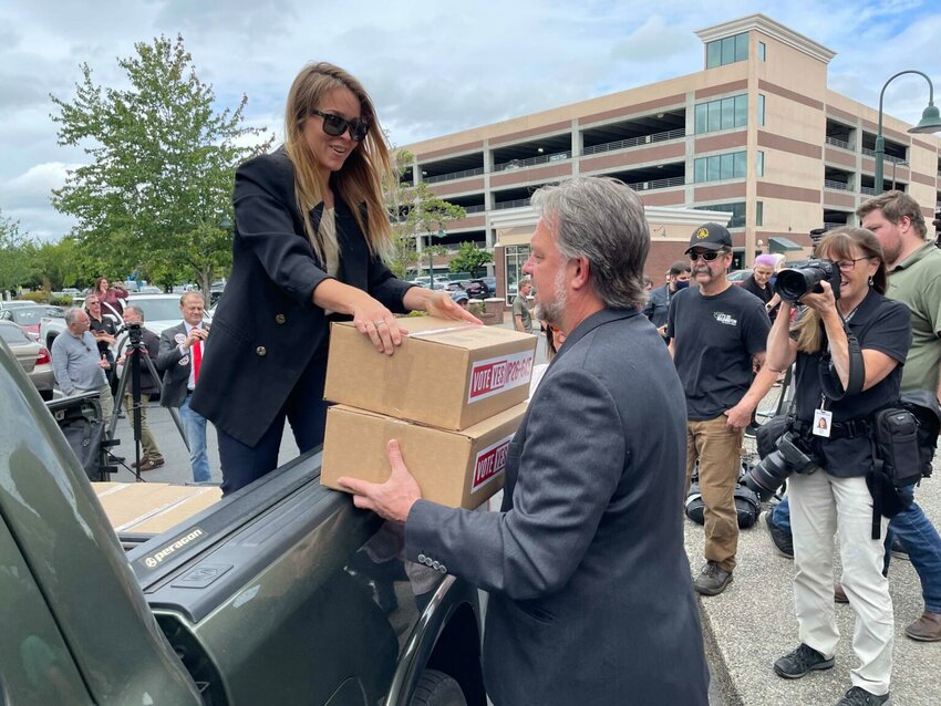 Ashley Butenschoen, a volunteer for Let&rsquo;s Go Washington, hands boxes of ballot initiative petitions to the group&rsquo;s founder, Brian Heywood.