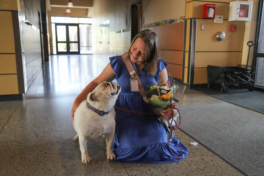 South Ridge Elementary School counselor Anne Lamping kneels beside Fergie in the hallway after the therapy dog&rsquo;s retirement ceremony.