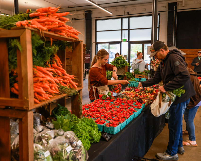 Marketgoers gather produce from White Clover Farm at the Battle Ground Farmers Market on Saturday, Sept. 19.